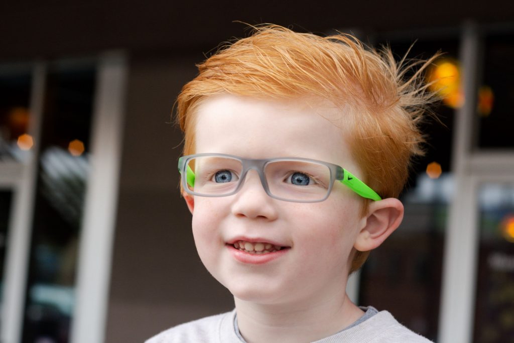 young boy wearing glasses and smiling 