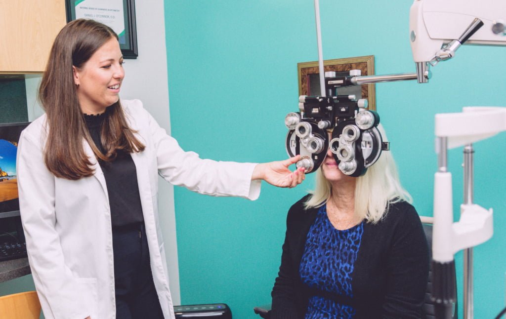 Eye doctor operating the phoropter with a patient during an eye exam 
