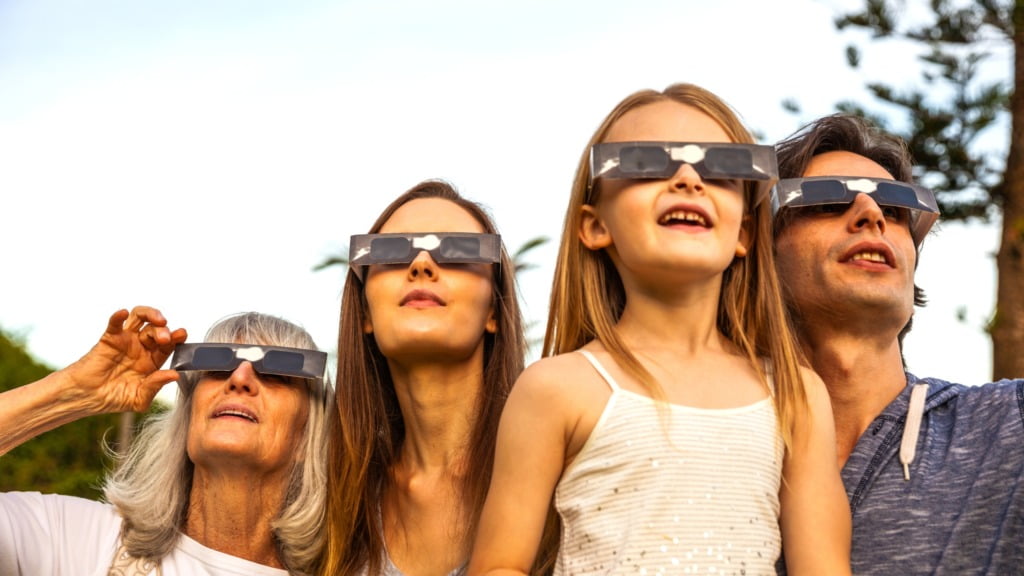 people wearing solar eclipse glasses looking up at the sky